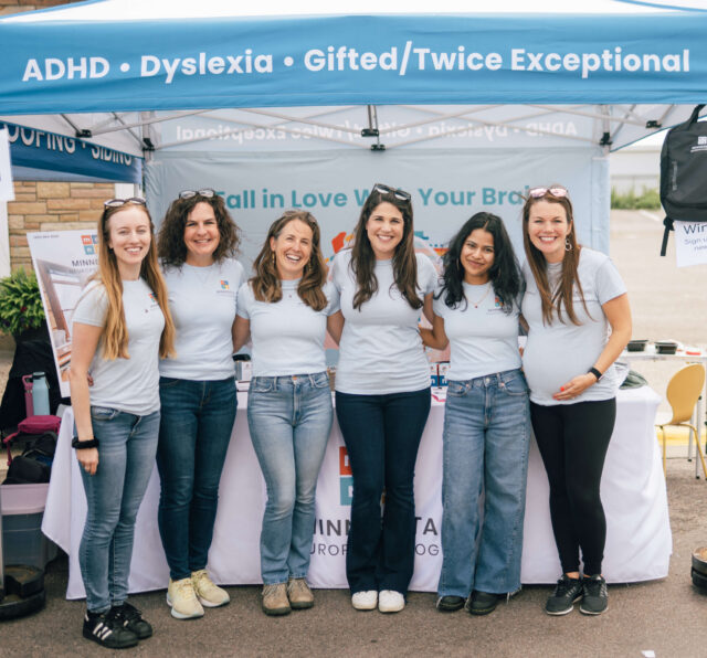 Team at ADHD and dyslexia testing booth with blue banner at community event