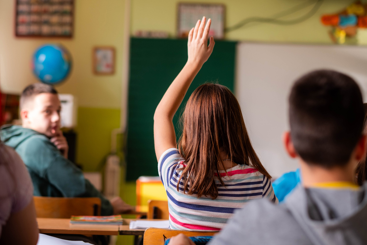 Girl in the classroom holding her hand up